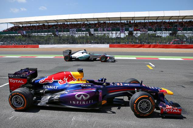 Нико Росберг проносится мимо замершего на стартовой прямой автомобиля Себастьяна Феттеля