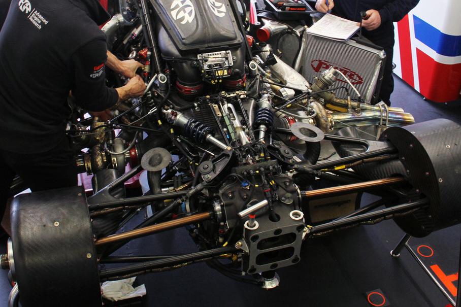 На фото хорошо видно «качалки» задней подвески и закрепленные на углепластиковом картере сцепления амортизаторы. Стабилизатор поперечной устойчивости выполнен в виде вертикального прута, проходящего сквозь картер сцепления. По бокам можно разглядеть турбокомпрессоры Garrett в теплоизоляции