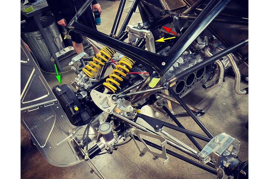 Самое интересное на снимке обозначено стрелками: жёлтой — подвижный кронштейн крепления амортизаторов задней подвески; красной — гидроцилиндр, изменяющий положение этого кронштейна; зелёной — раздаточная коробка, от которой уходит карданный вал к переднему редутору.
Картер коробки передач выполняет несущую функцию: к нему крепится задняя подвеска